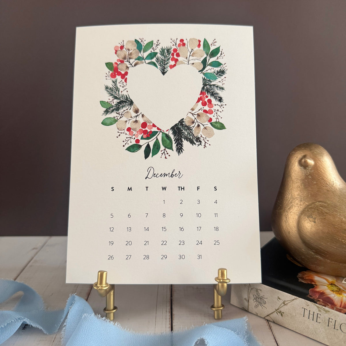 December page with a heart wreath of evergreen, red berries and winter blooms